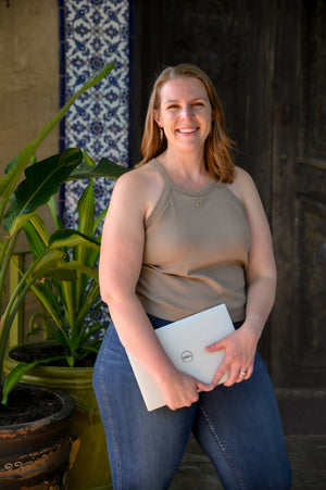 Hem founder Lauren smiling outdoors, holding a laptop, beside a note sharing her journey with pelvic organ prolapse.