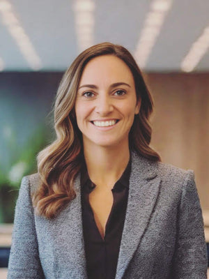 Woman in a gray blazer smiling in an indoor setting