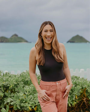 Woman standing in front of a scenic ocean view with islands.